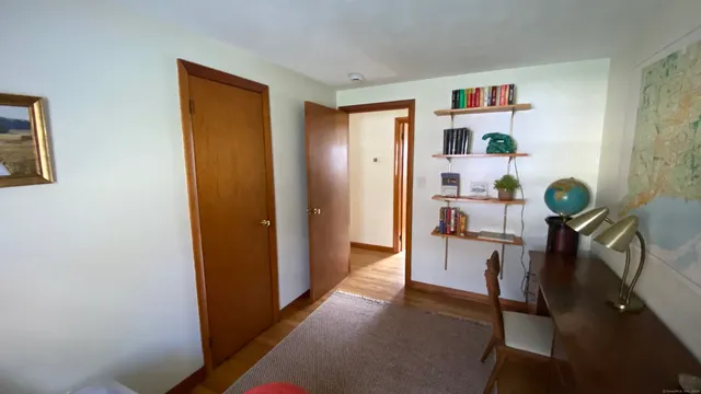 a view of a hallway to room with workspace and window