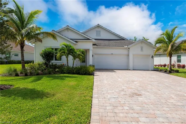 a view of a house with a yard and palm trees