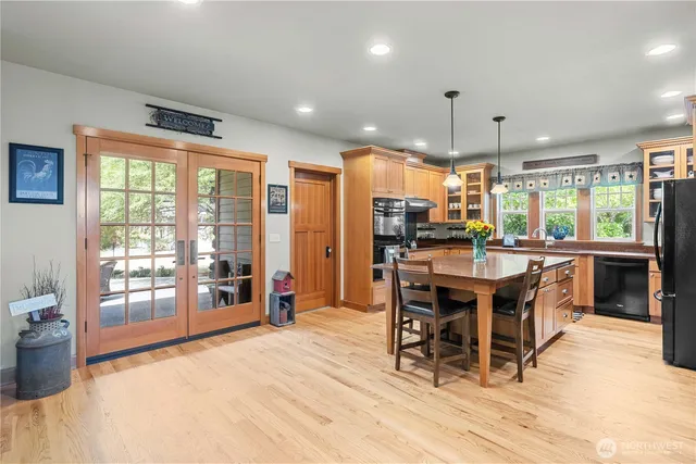 a kitchen with stainless steel appliances kitchen island granite countertop a table chairs and a refrigerator