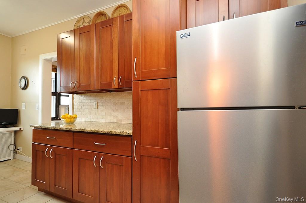 143 Garth Road, Unit 5J Scarsdale, NY 10583 - Photo 12 of 47 a kitchen with a refrigerator and cabinets
