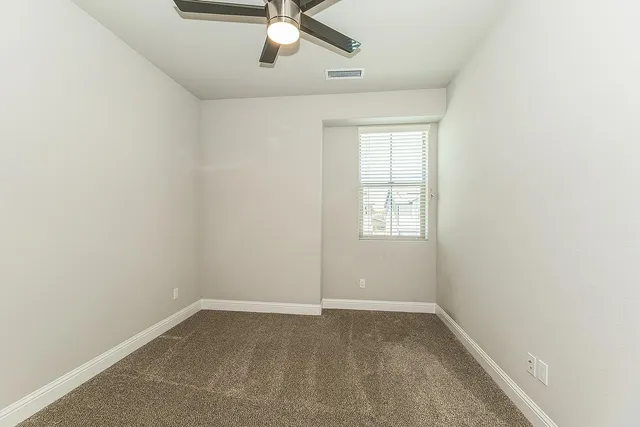 an empty room with a window and a fan