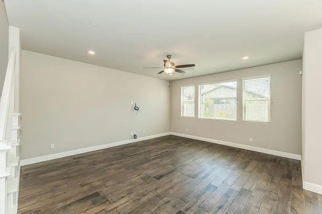 a view of an empty room with a window and wooden floor