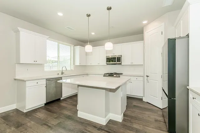 a kitchen with stainless steel appliances granite countertop a sink a stove a refrigerator and island with wooden floor