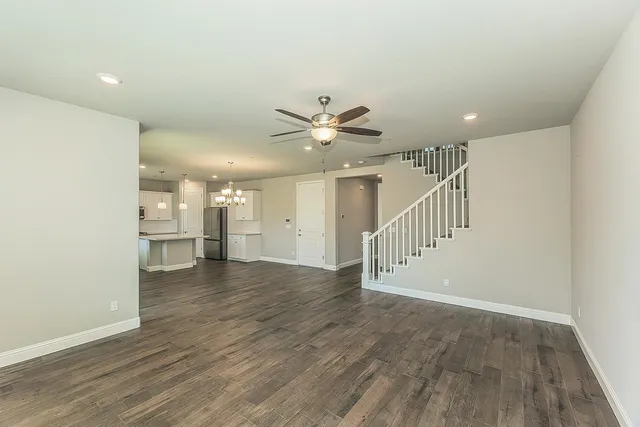 a view of an empty room with wooden floor and a ceiling fan