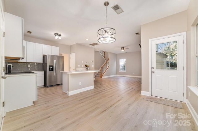 a view of a kitchen with a refrigerator a stove top oven a sink cabinets and wooden floor