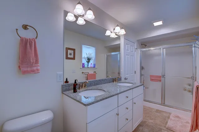 a bathroom with a granite countertop sink a toilet and a mirror
