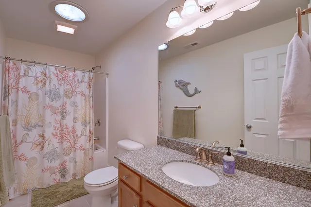 a bathroom with a granite countertop sink toilet a mirror and shower curtain