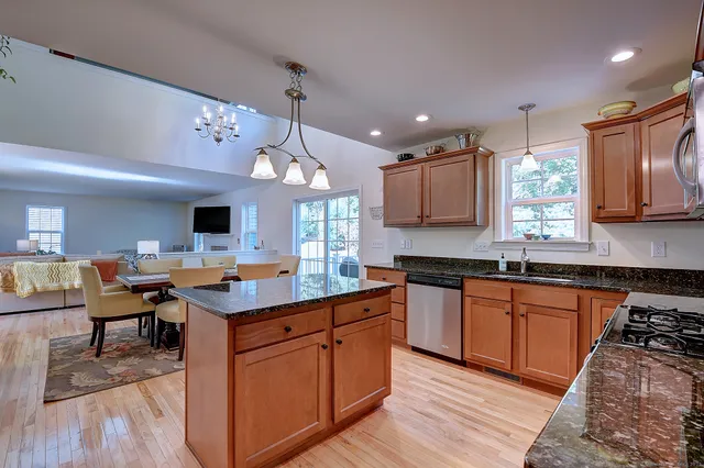 a kitchen with stainless steel appliances granite countertop a sink a stove and a wooden floors