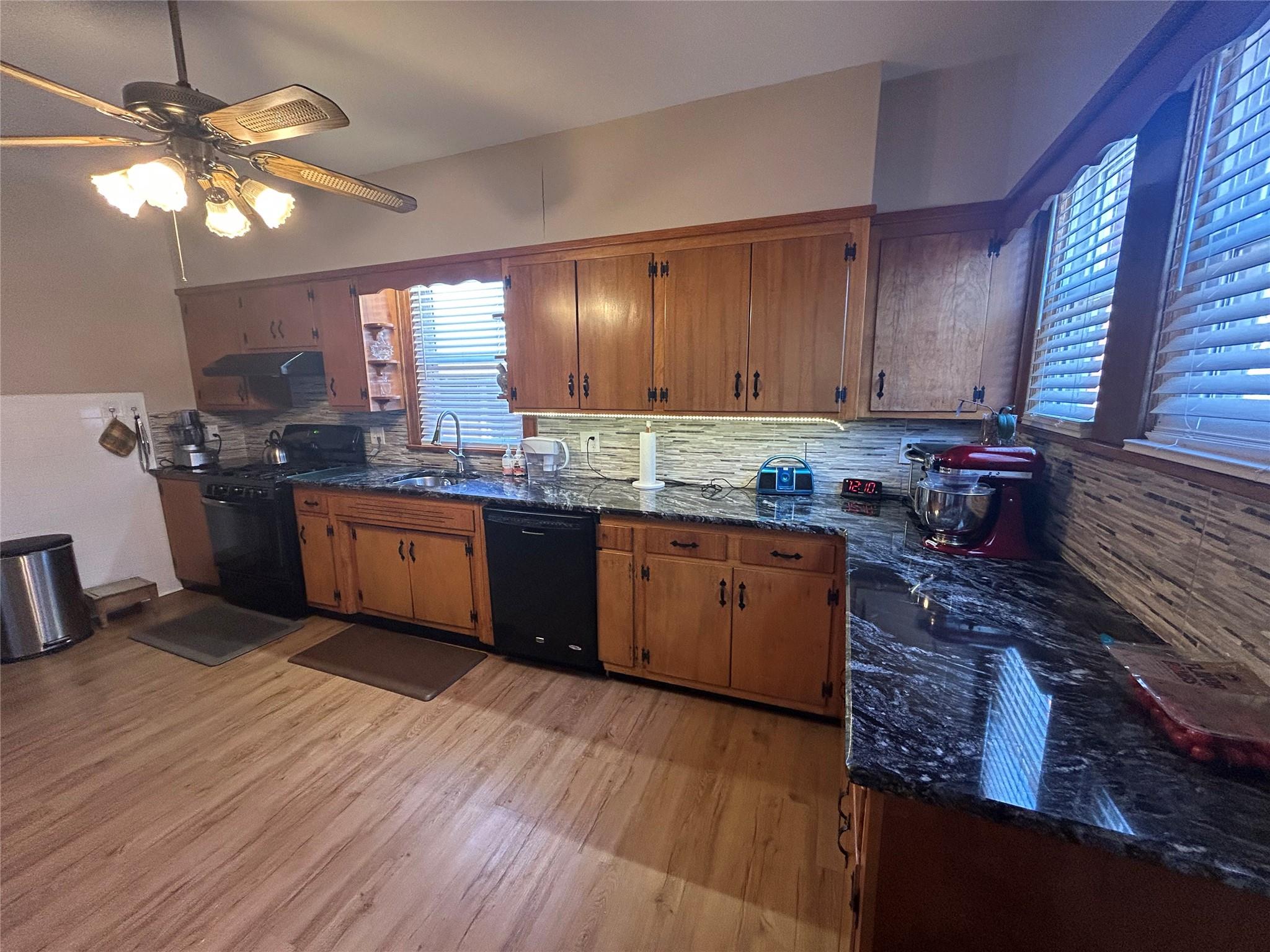 199 Washington Street Poughkeepsie, NY 12601 - Photo 3 of 32 Kitchen with under cabinet range hood, light wood-type flooring, backsplash, brown cabinets, and black appliances