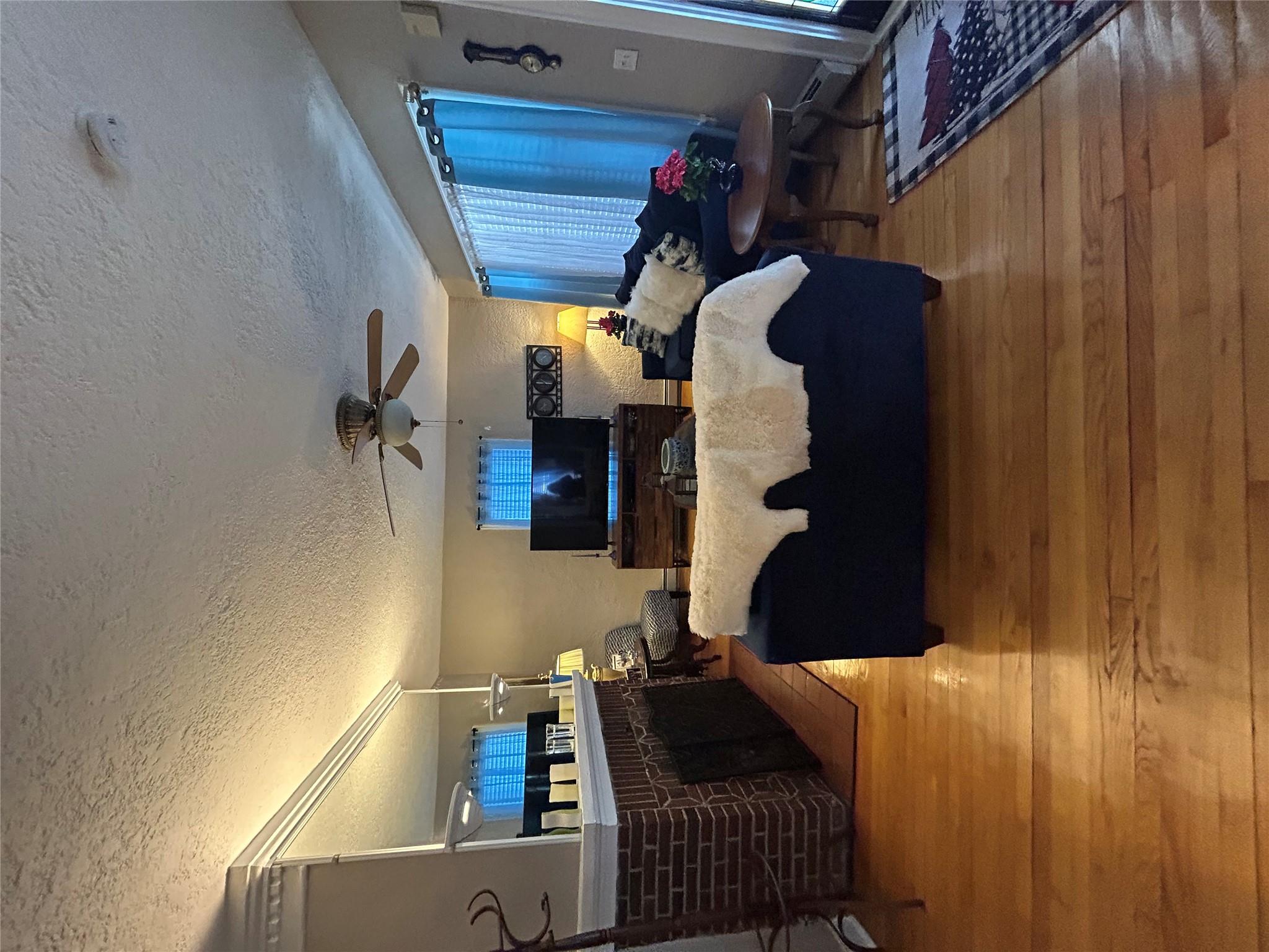 199 Washington Street Poughkeepsie, NY 12601 - Photo 7 of 32 Living room with a brick fireplace, a ceiling fan, a textured ceiling, light wood-style floors, and a baseboard heating unit