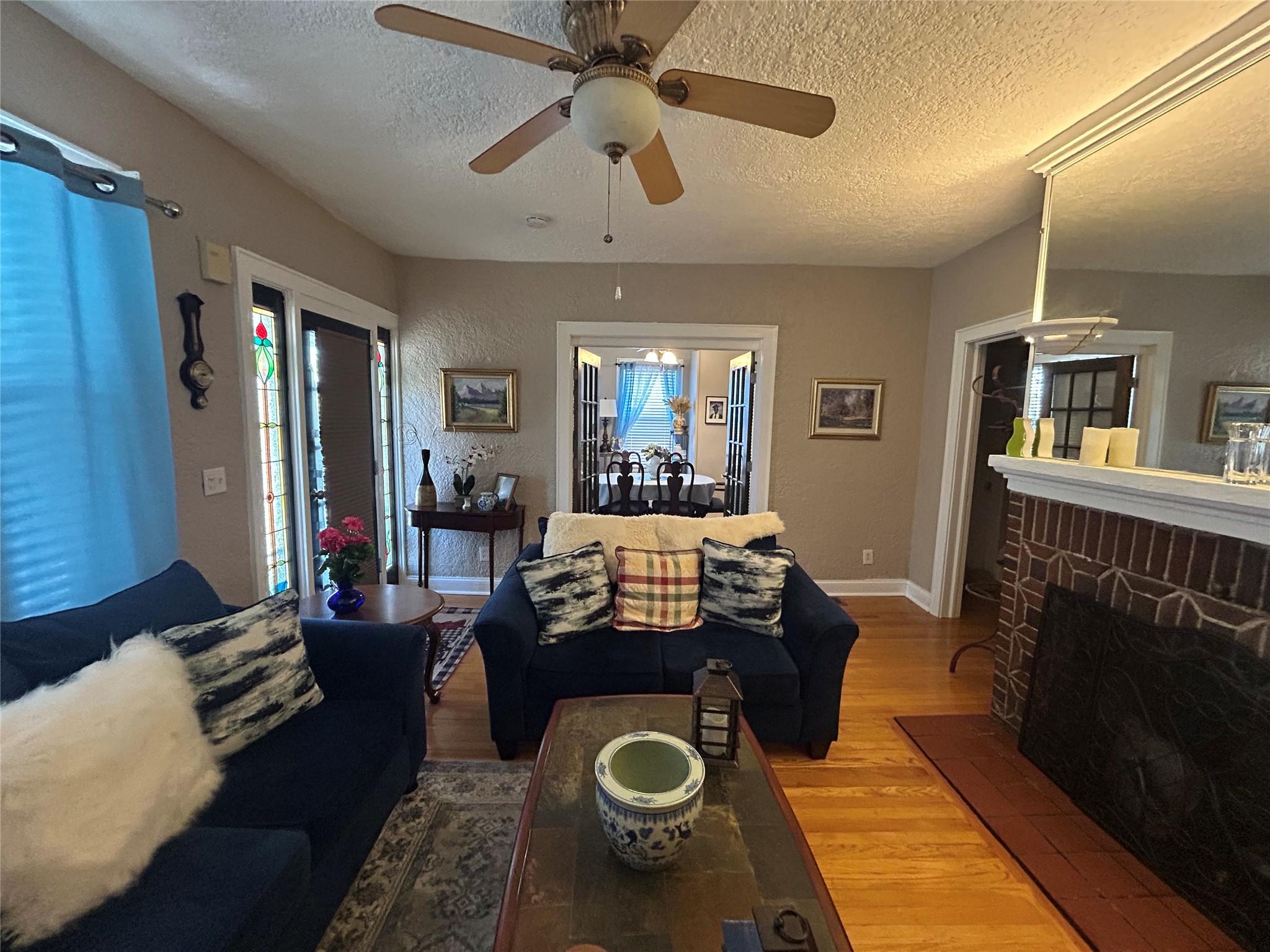 199 Washington Street Poughkeepsie, NY 12601 - Photo 8 of 32 Living room featuring a brick fireplace, a textured ceiling, baseboards, and wood finished floors
