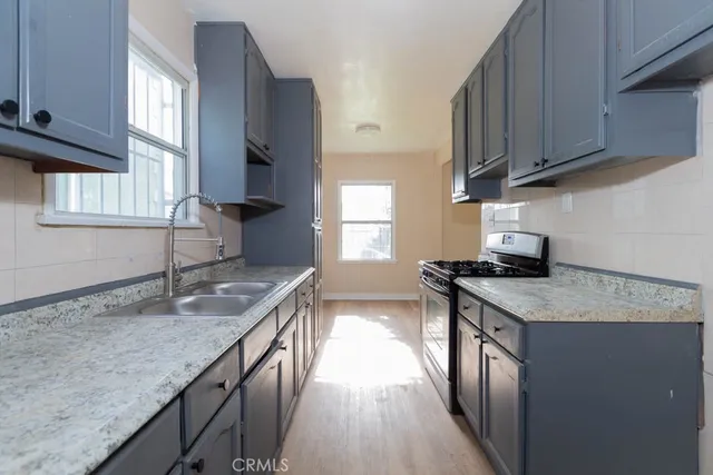 a kitchen with granite countertop a sink stove and cabinets