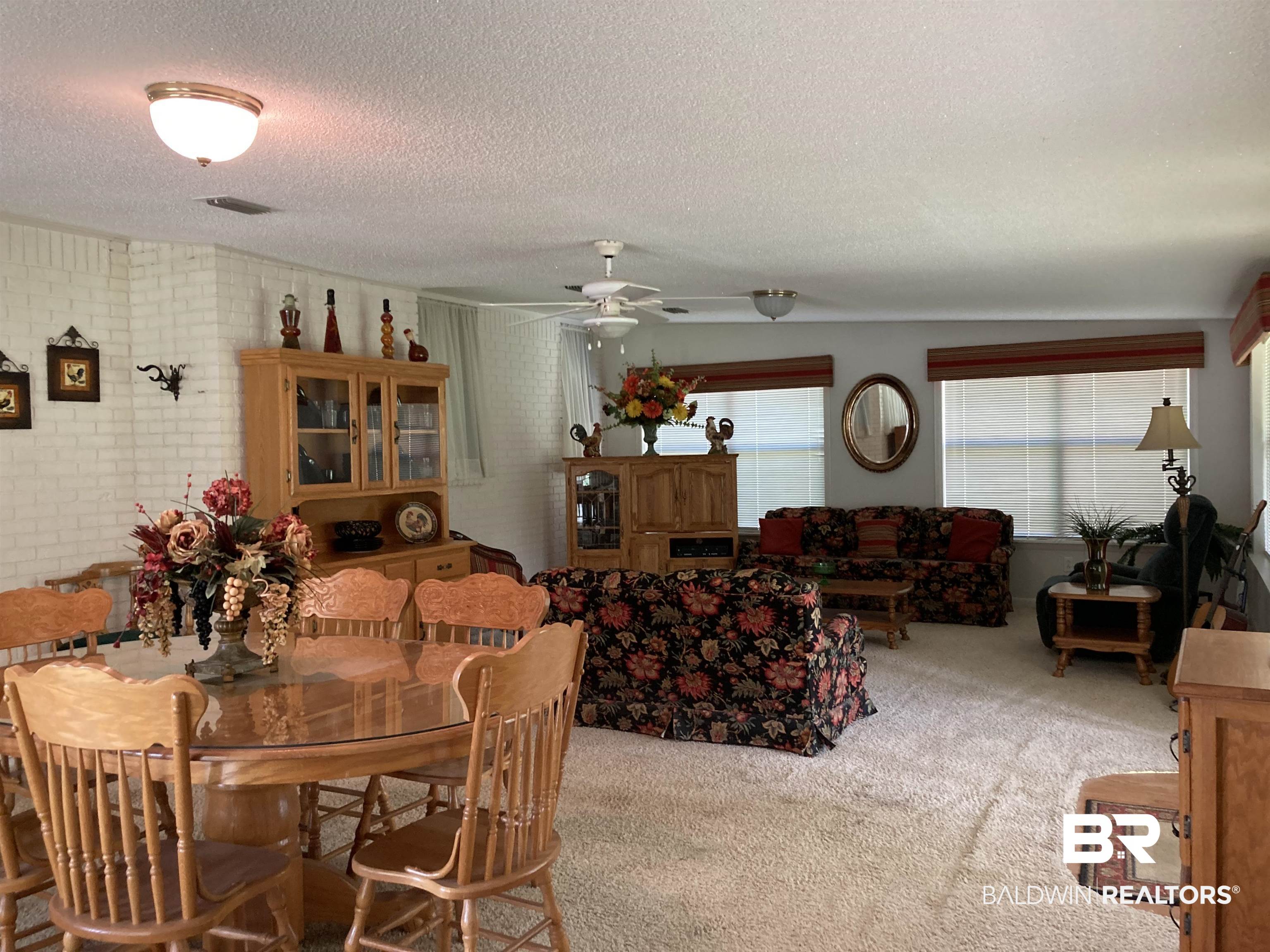 6151 Meadows Road Walnut Hill, FL 32568 - Photo 9 of 29 Dining room featuring carpet, a textured ceiling, ceiling fan, and brick wall