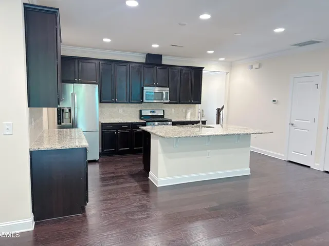 a kitchen with kitchen island granite countertop wooden cabinets and stainless steel appliances