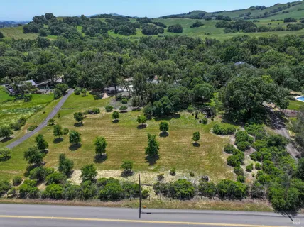 an aerial view of residential houses with outdoor space and trees