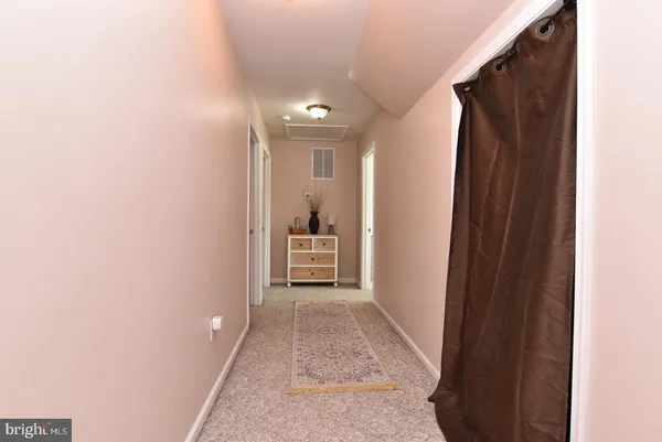 a view of a hallway with wooden floor and a bathroom