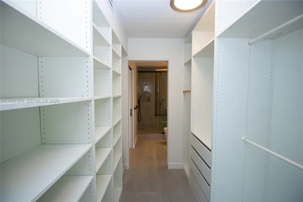 a view of hallway with walk in closet and wooden floor