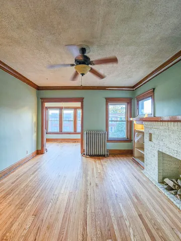 a view of empty room with fireplace and wooden floor
