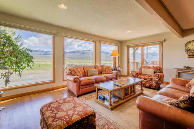 a view of a dining room with furniture a kitchen view and large windows