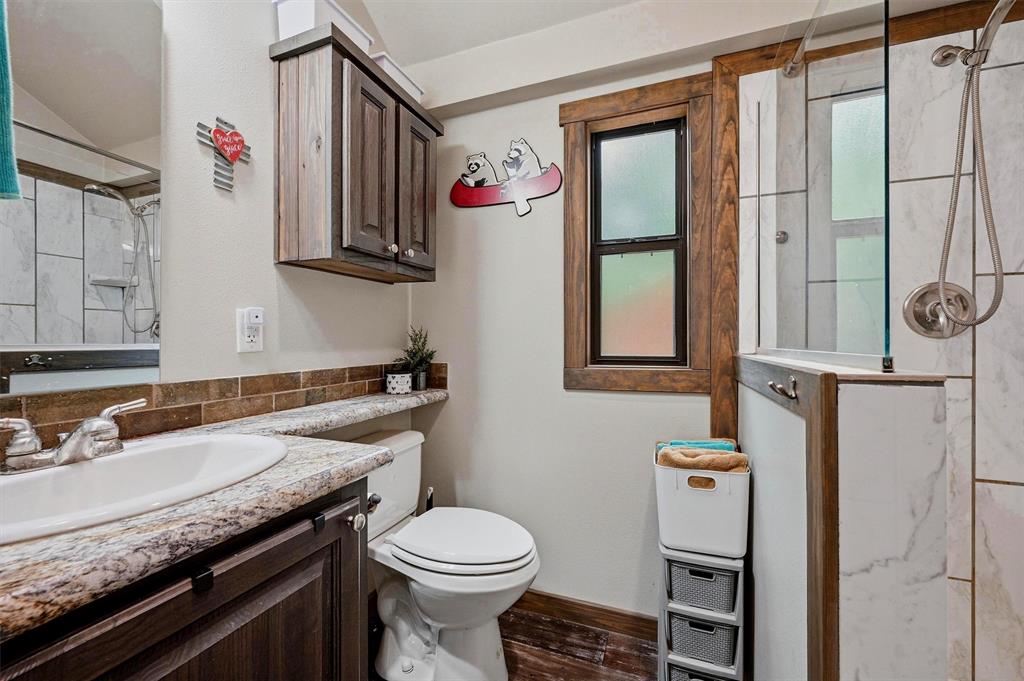 3958 Ranch Road Whitesboro, TX 76273 - Photo 17 of 40 Bathroom featuring a dark wood-finish vanity with an integrated sink, granite-look countertop, and brick-patterned tile backsplash