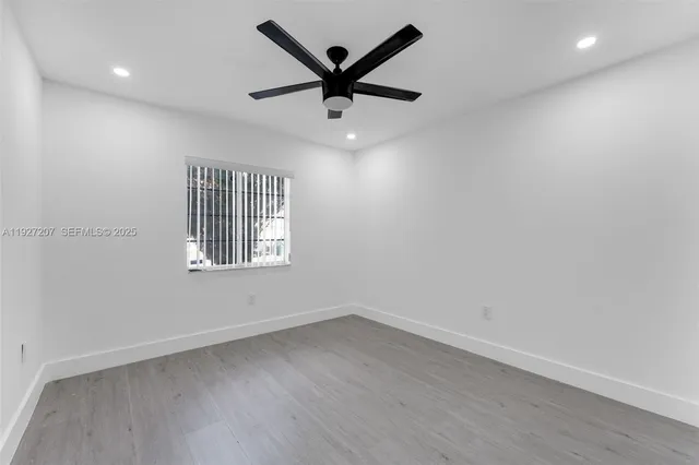an empty room with a window and a ceiling fan