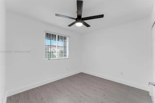 an empty room with a ceiling fan and a window