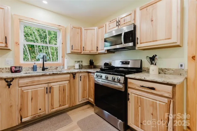 a kitchen with stainless steel appliances granite countertop a sink and a stove