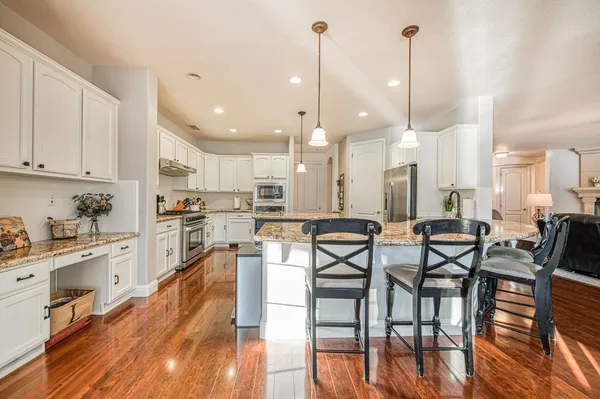 a kitchen with stainless steel appliances granite countertop a refrigerator a sink and a wooden floors