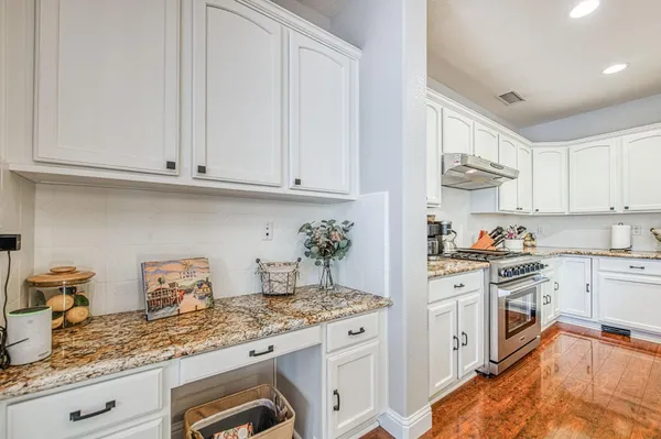 a kitchen with stainless steel appliances granite countertop a sink a stove a refrigerator and island with wooden floor