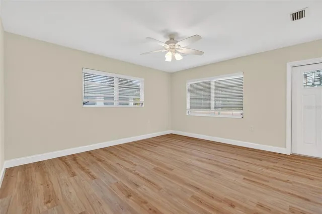 a view of an empty room with wooden floor and a window
