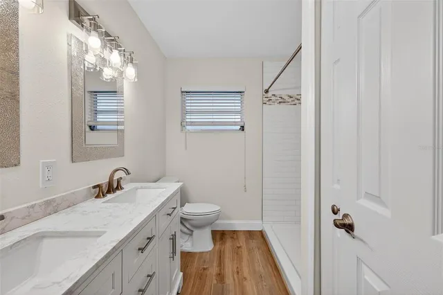 a bathroom with a granite countertop sink toilet a mirror and shower