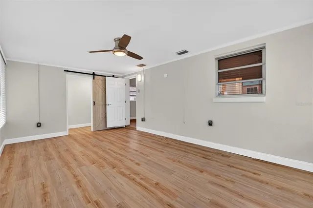 a view of empty room with wooden floor and fan
