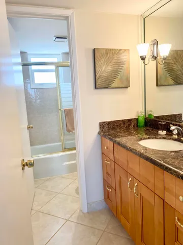 a bathroom with a granite countertop sink a mirror and shower