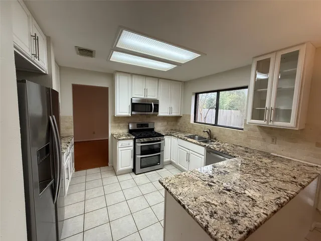 a kitchen with stainless steel appliances granite countertop a refrigerator oven stove a sink dishwasher and a refrigerator