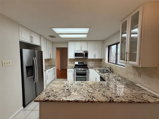 a kitchen with granite countertop a refrigerator and a stove top oven