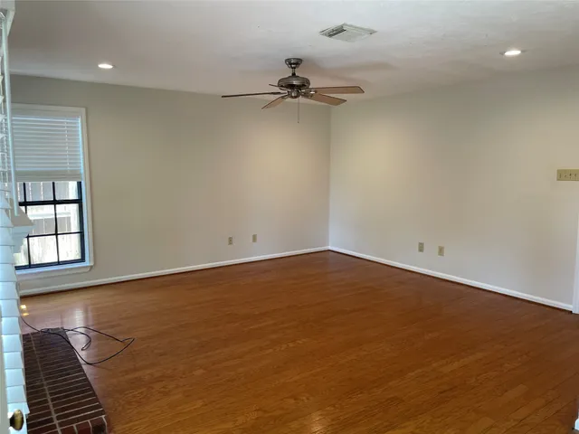 an empty room with wooden floor fireplace and windows