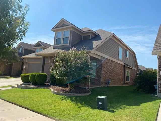 a front view of a house with a yard and a large tree