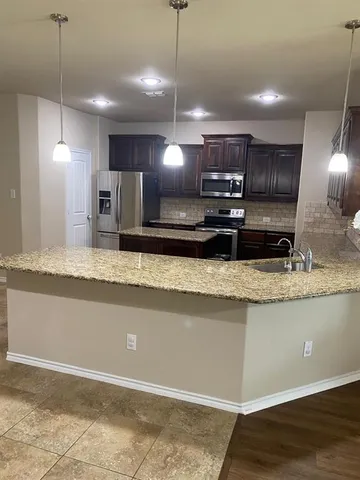 a large kitchen with kitchen island a sink a counter space and a refrigerator