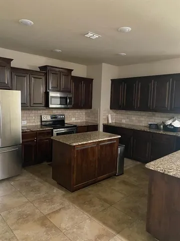 a kitchen with stainless steel appliances granite countertop a stove a sink and a refrigerator