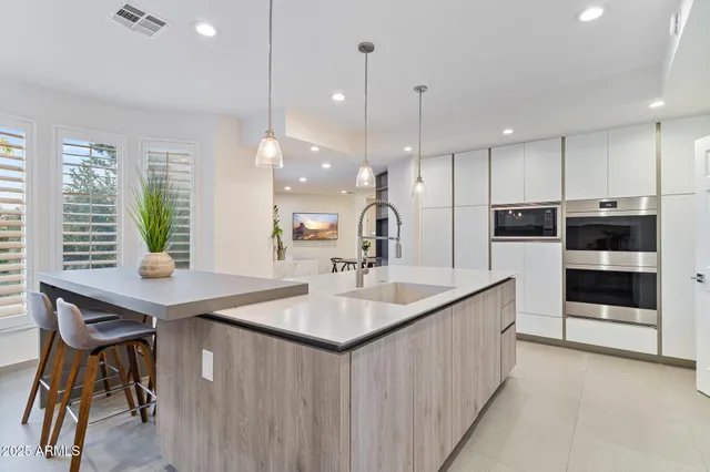 a kitchen with stainless steel appliances kitchen island granite countertop a dining table chairs and white cabinets