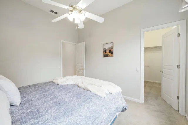 a bedroom with a large bed and a chandelier fan