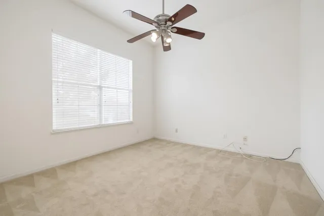an empty room with a window and a fan
