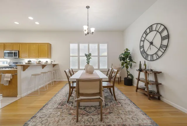 a dining room with chandelier fan and wooden floor