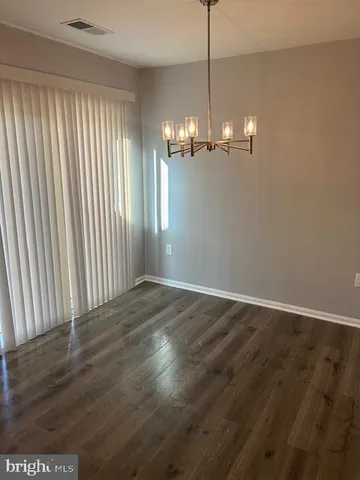 an empty room with wooden floor chandelier and windows