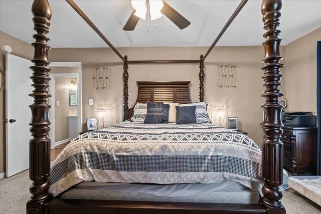 a large bed sitting in a bedroom next to a window with a lamp and a large window