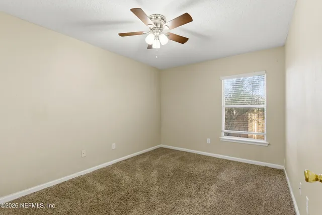an empty room with a window and a ceiling fan