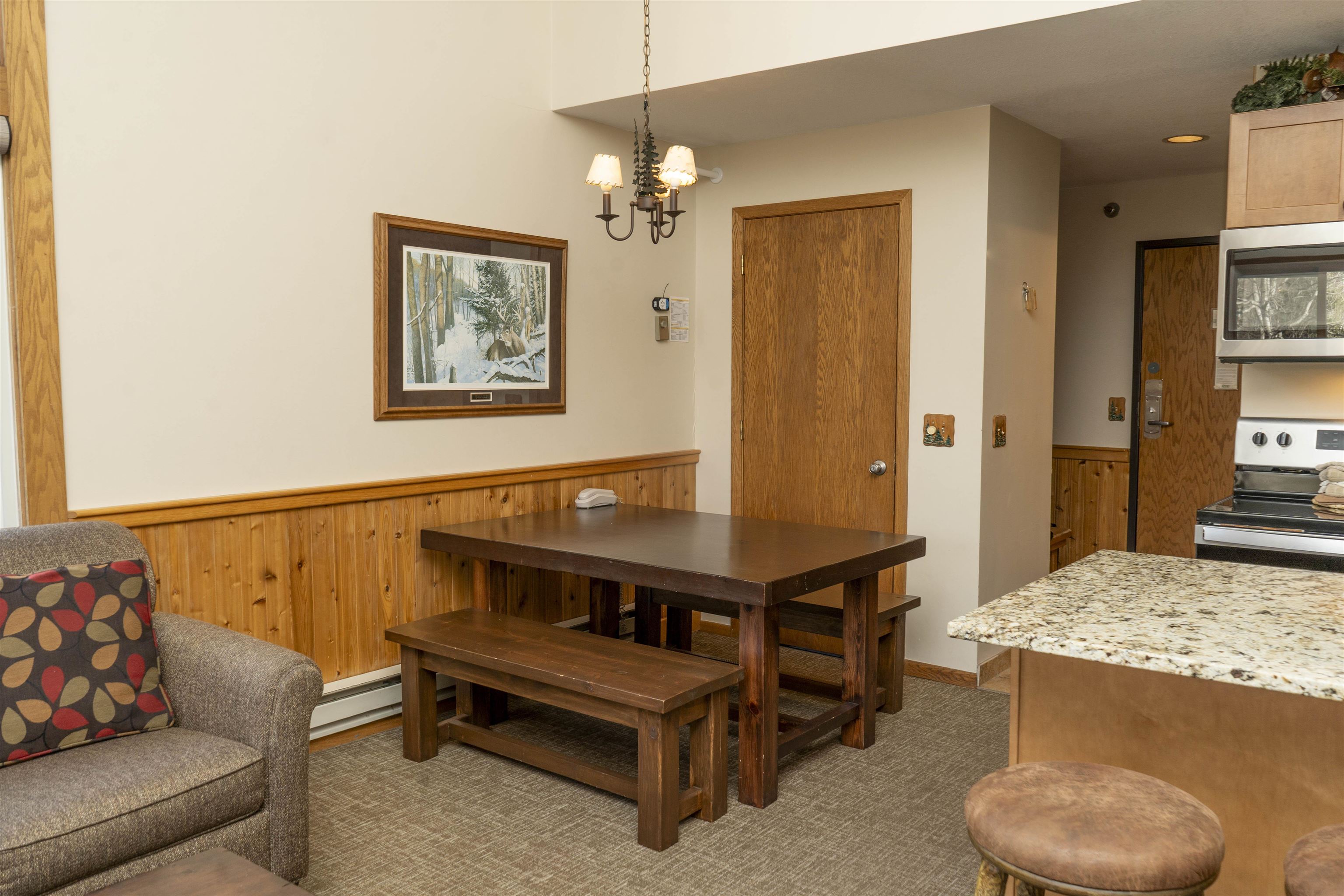 111 Bridge Run Lane, Unit 111 Lutsen, MN 55612 - Photo 12 of 48 Dining area with wood walls, a wainscoted wall, a chandelier, baseboard heating, and light colored carpet