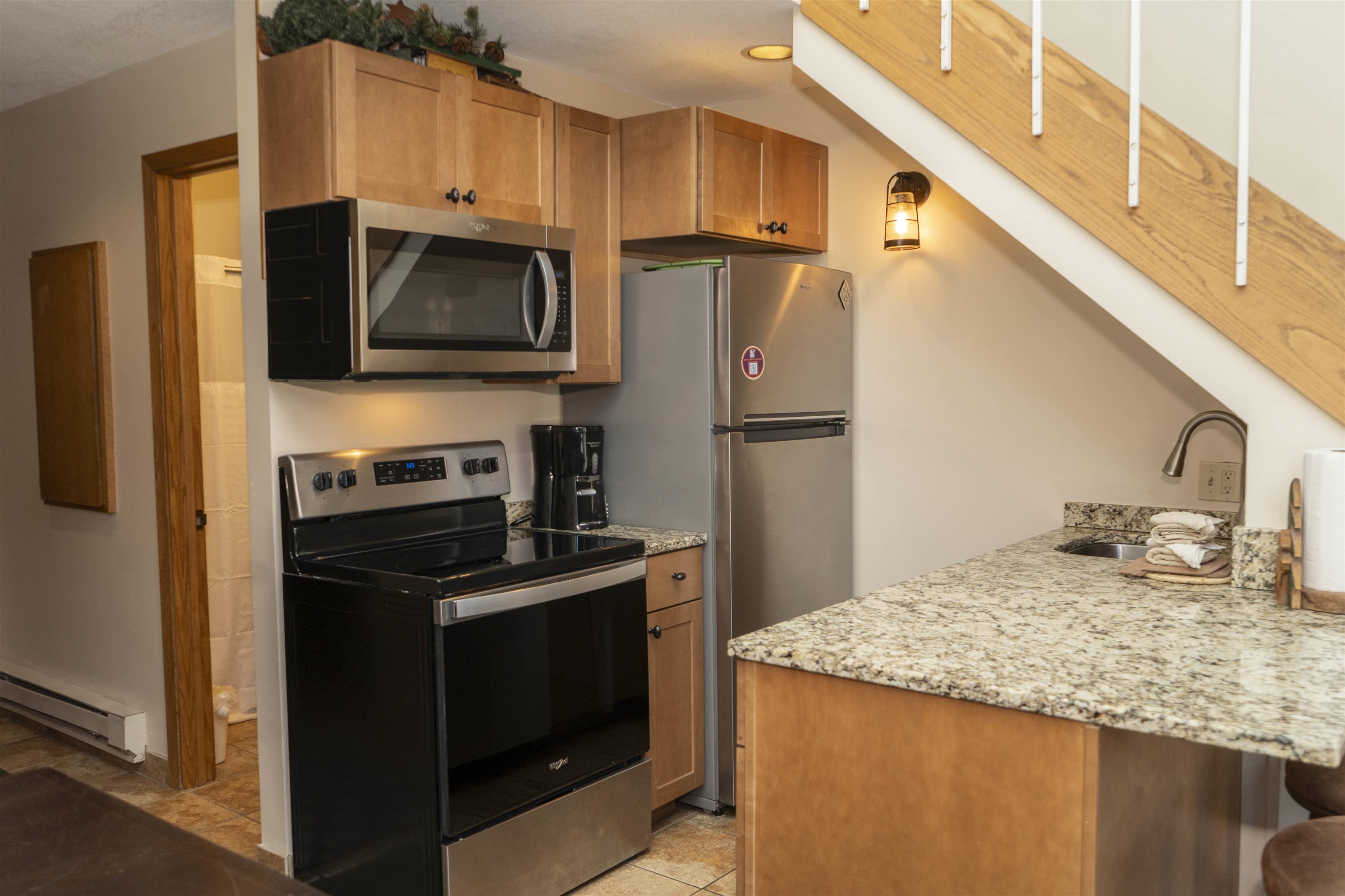 111 Bridge Run Lane, Unit 111 Lutsen, MN 55612 - Photo 24 of 48 Kitchen featuring appliances with stainless steel finishes, light stone counters, a breakfast bar area, and brown cabinetry