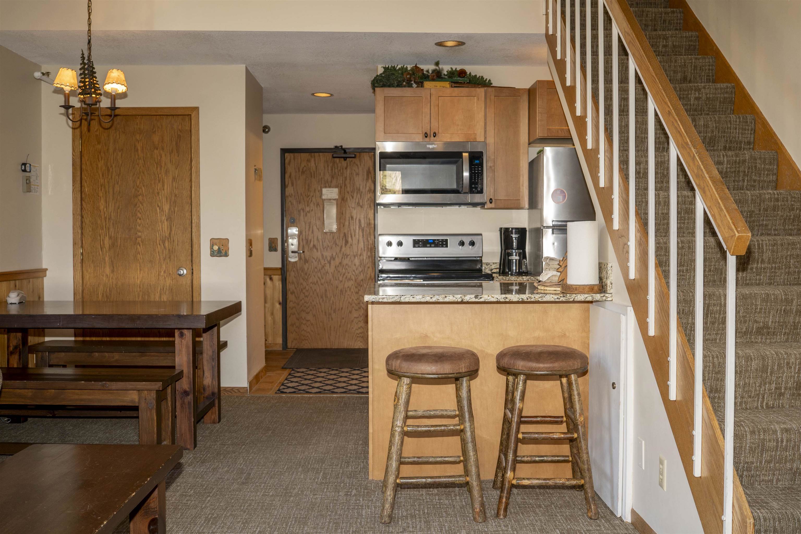 111 Bridge Run Lane, Unit 111 Lutsen, MN 55612 - Photo 4 of 48 Kitchen featuring decorative light fixtures, appliances with stainless steel finishes, a breakfast bar, light stone countertops, and a peninsula