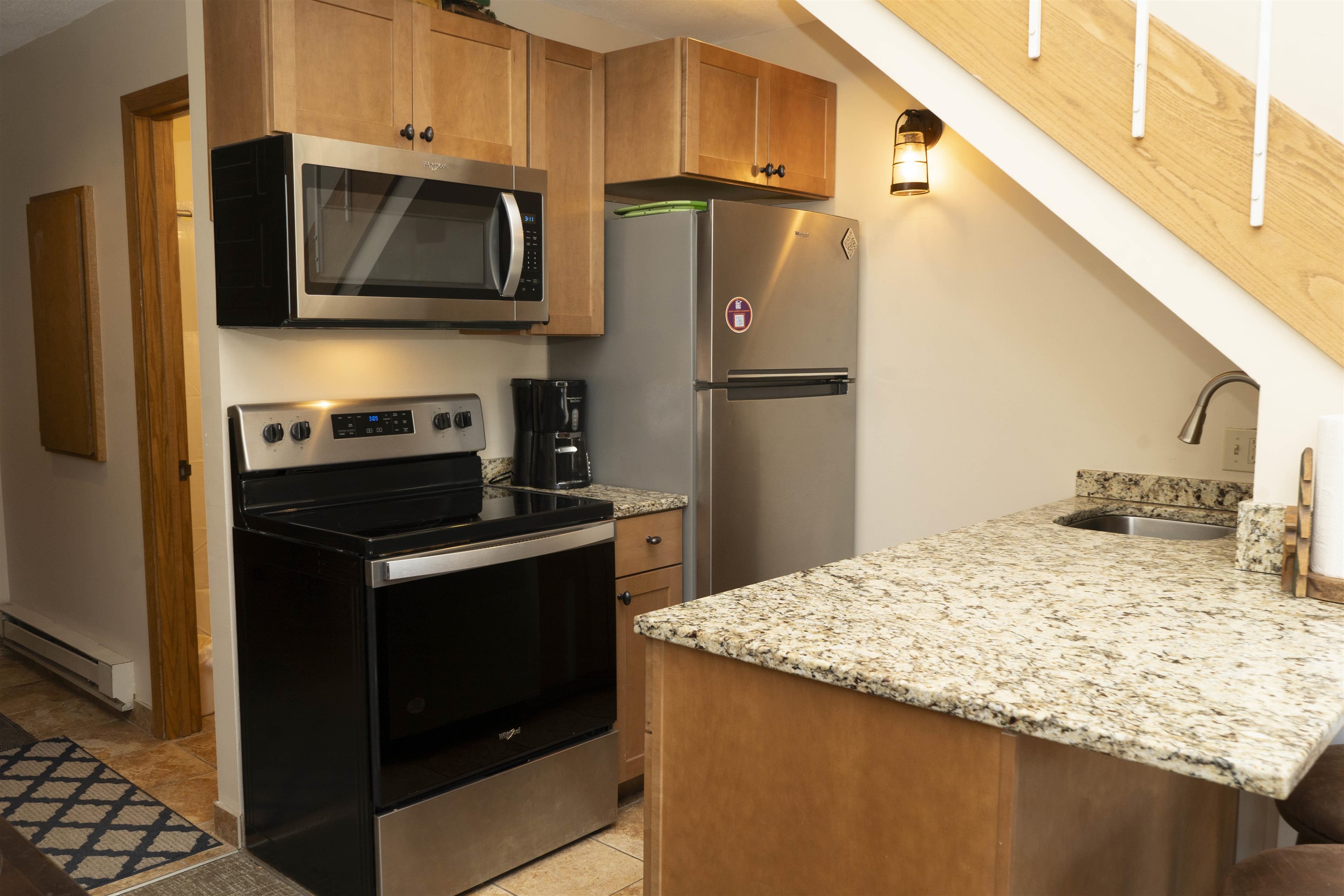 111 Bridge Run Lane, Unit 111 Lutsen, MN 55612 - Photo 6 of 48 Kitchen featuring appliances with stainless steel finishes, light stone countertops, baseboard heating, and a peninsula